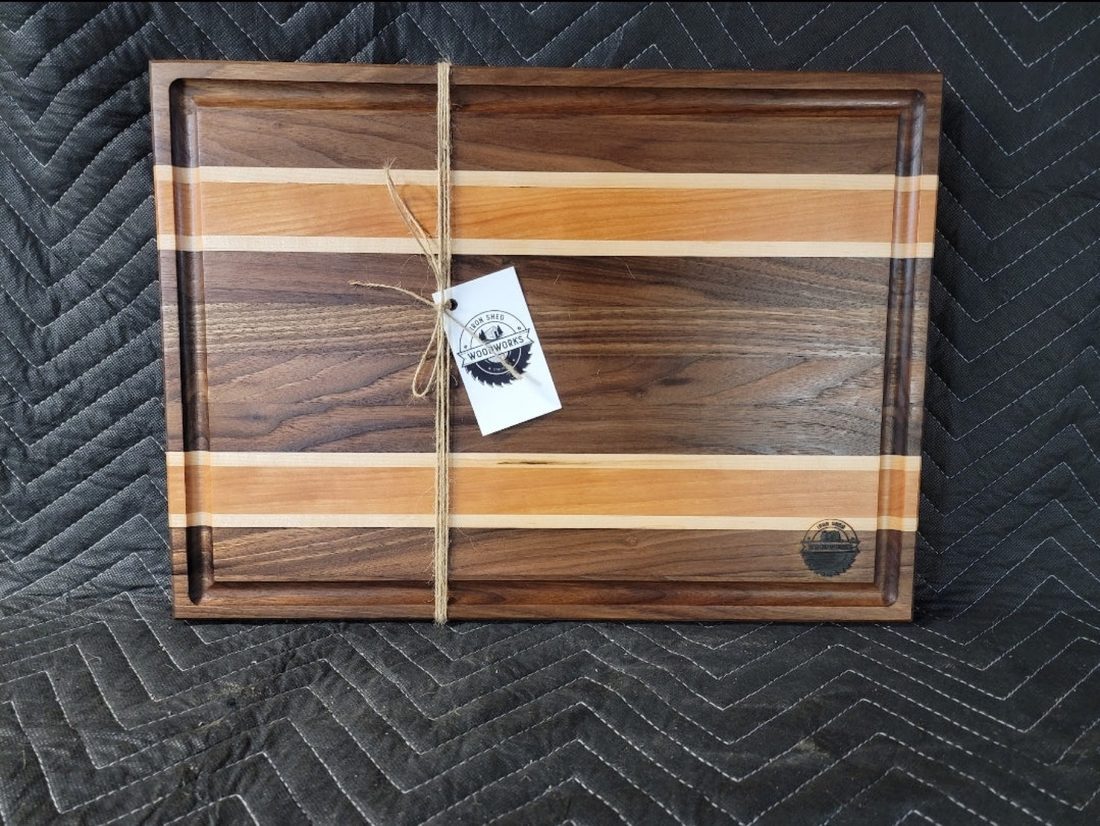 Walnut, cherry, and maple triple-stripe cutting board with a carved juice groove